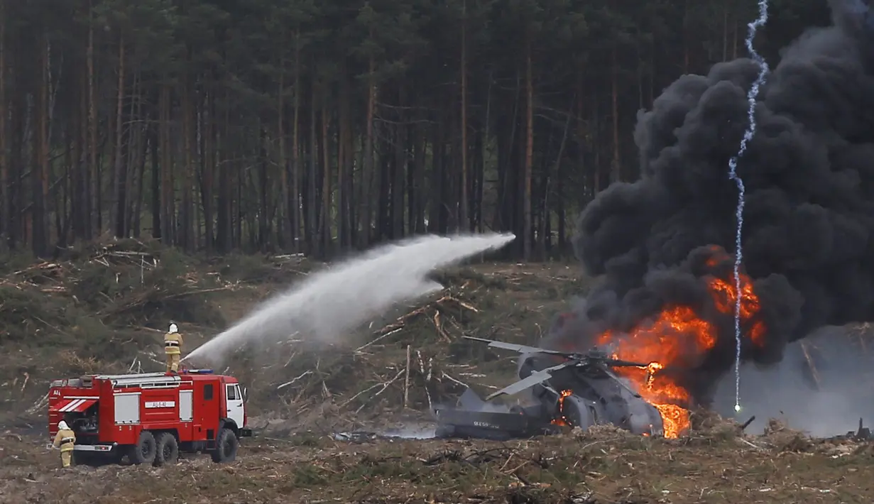 Pemadam kebakaran berupaya memadamkan helikopter Mi-28N yang jatuh terbakar saat kompetisi penerbangan militer "Aviadarts" di Dubrovichi, Rusia, Minggu (2/8/2015). Akibat kejadian tersebut, satu dari dua orang pilot tewas. (REUTERS/Maxim Shemetov)