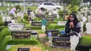 Suasana haru terlihat saat peziarah memanjatkan doa di sisi pusara makam keluarga. (JUNI KRISWANTO/AFP)