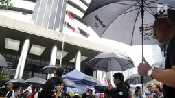 Massa Serikat Pekerja JICT dan FPPI berunjuk rasa di depan Gedung KPK, Jakarta, Selasa (18/12). Massa berunjuk rasa sambil mengenakan payung hitam. (Merdeka.com/Dwi Narwoko)