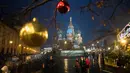 Wisatawan berjalan di kawasan Lapangan Merah atau Red Square dengan latar belakang Katedral St. Basil di Moskow, Rusia, Senin (18/12). Kawasan Red Square didekorasi dengan lampu dan pernak-pernik perayaan Natal dan Tahun Baru. (AP Photo/Pavel Golovkin)