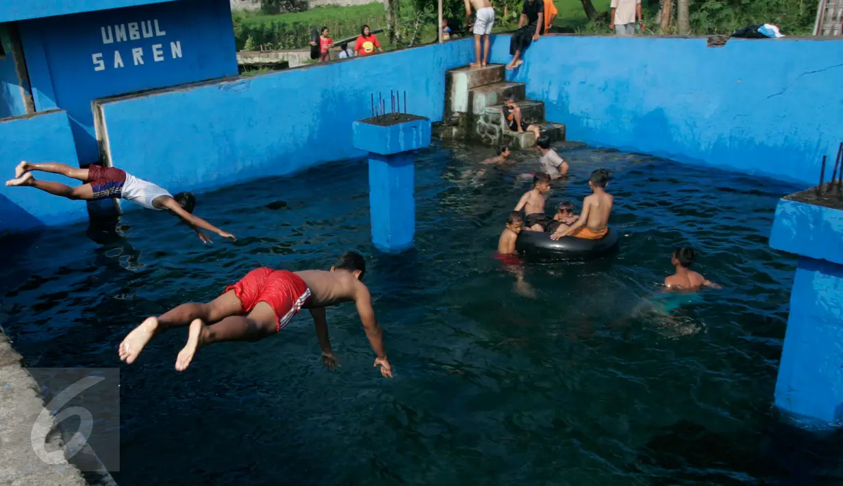 Dua orang anak melompat ke kolam pemandian Umbul Saren di Wedomartani, Sleman, Minggu (5/6). Pengunjung memadati kolam pemandian tersebut untuk melaksanakan tradisi "padusan" menjelang Ramadan 2016. (Liputan6.com/Boy Harjanto)