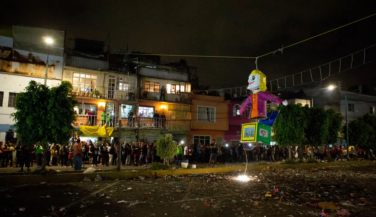 Warga menonton Jack in the box dengan karakter Donald Trump yang akan dibakar dalam perayaan pembakaran Yudas di Mexico City, Meksiko (15/4). Warga membakar gambar-gambar dan patung untuk mewakili Yudas Iskariot.  (AP Photo/Rebecca Blackwell)