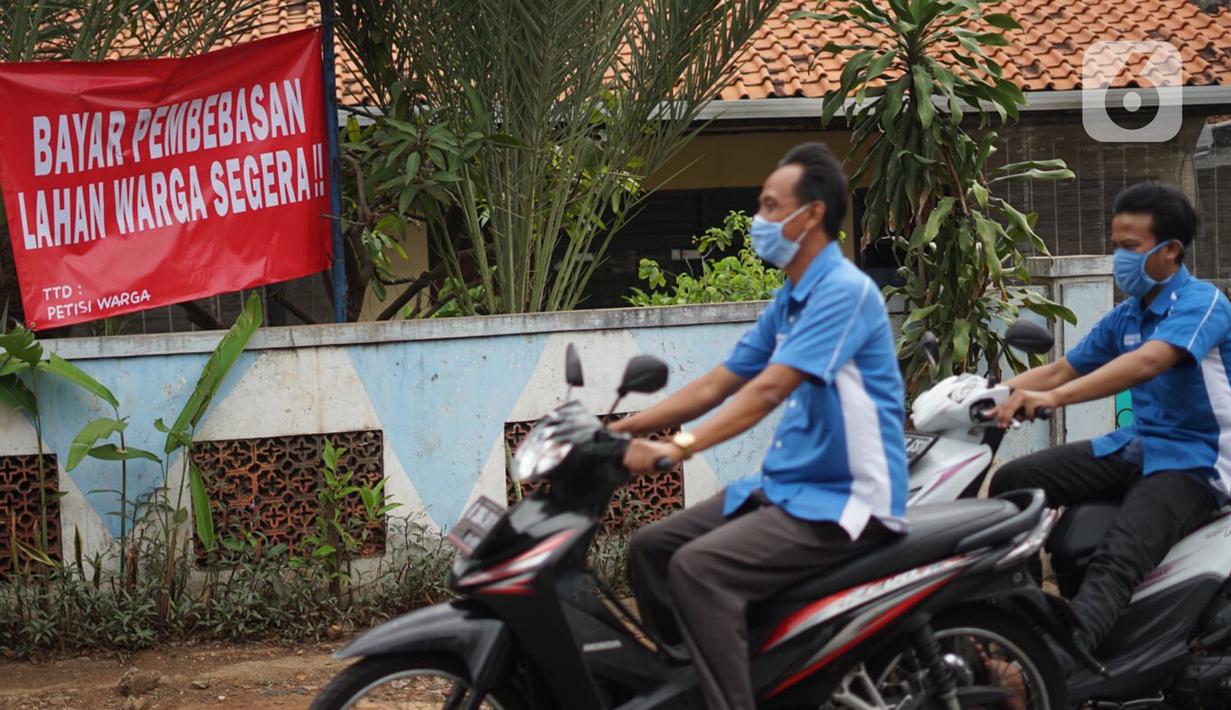 Pengendara motor melintas di depan poster protes warga terhadap pembangunan flyover di kawasan Tanjung Barat, Jakarta, Rabu (15/7/2020). Dalam poster protes tersebut, warga menuntut agar pembayaran pelunasan pembebasan lahan segera diselesaikan secara serentak. (Liputan6.com/Immanuel Antonius)