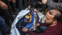 Kerabat dan teman berduka di depan jenazah Saif Abu Taha, seorang anggota staf kelompok bantuan World Central Kitchen yang berbasis di AS yang terbunuh ketika serangan Israel menghantam konvoi LSM yang mengirimkan bantuan makanan di Gaza sehari sebelumnya, saat pemakamannya di Rafah di Jalur Gaza selatan pada 2 April 2024. (SAID KHATIB/AFP)