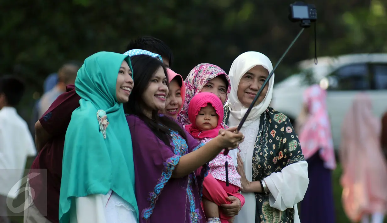 Warga berfoto keluarga secara selfie usai melaksanakan Salat Idul Fitri 1437 H di Kebun Raya Bogor, Rabu (6/7). Pemerintah Kota Bogor menyelenggarakan Salat Idul Fitri 1437 H yang dipusatkan di areal Kebun Raya. (Liputan6.com/Helmi Fithriansyah)