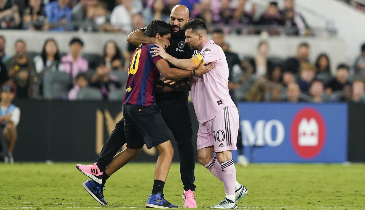 <p>Bodyguard Lionel Messi, Yassine Chueko, kembali jadi sorotan. Dia dengan sigap meringkus fans yang menerobos lapangan demi bisa memeluk La Pulga saat Inter Miami bertandang ke markas Los Angeles FC dalam lanjutan Major League Soccer, Senin (4/9/2023). (AP Photo/Ryan Sun)</p>