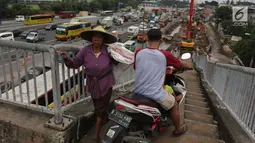 Pengendara motor melintas di samping pejalan kaki menuruni Jembatan Penyeberangan Orang (JPO) kawasan Cikunir, Bekasi Barat, Senin (12/3). Di jembatan ini pejalan kaki dan pemotor saling berebut melintas. (Liputan6.com/Arya Manggala)