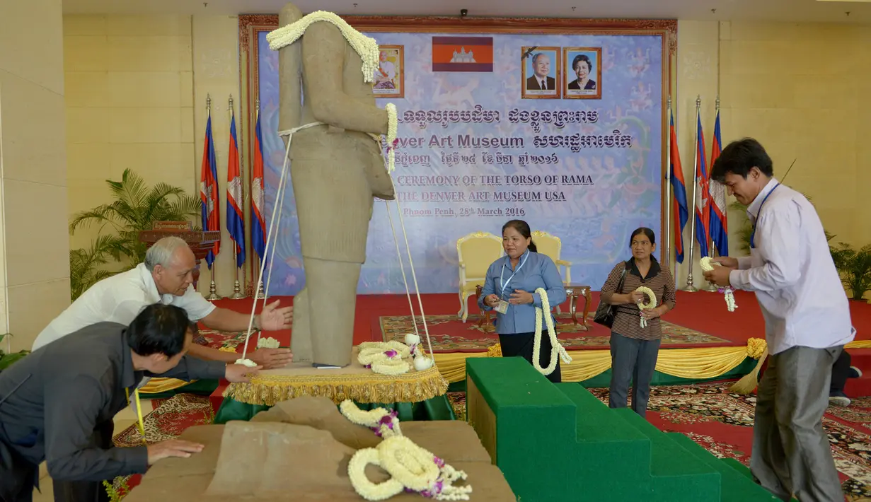 Perwakilan Kamboja berdiri di dekat patung Dewa Rama abad ke-10 yang dikembalikan Museum Seni Denver, AS, dalam sebuah upacara di Phnom Penh, Senin (28/3). Patung setinggi 1,5 meter itu dicuri pada era 1970-an dari Candi Koh Ker. (TANG CHHIN SOTHY/AFP)