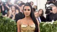 Aktris Kim Kardashian berpose saat menghadiri Met Gala 2018 di Metropolitan Museum of Art, New York (7/5). Kim Kardashian tampil seksi mengenakan gaun emas super ketat. (AP Photo/Evan Agostini)