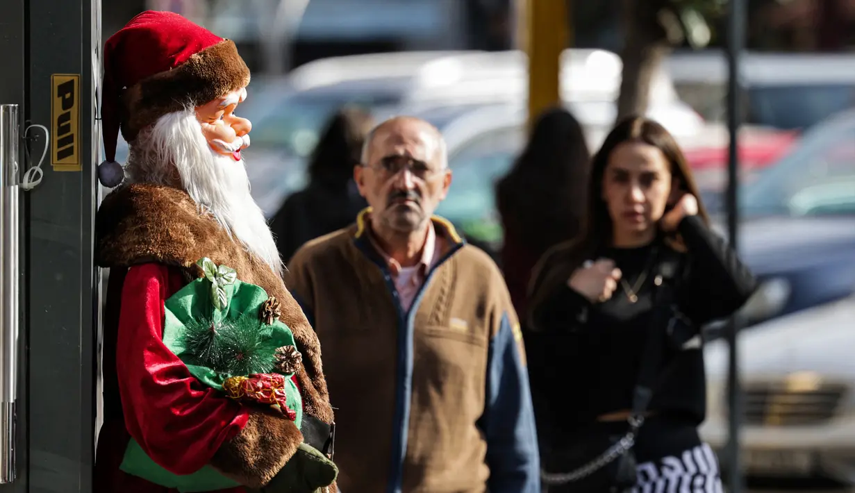 Pemandangan patung Santo Nikolas (Bapa Natal atau Sinterklas) di luar pintu masuk toko mainan di kawasan Burj Hammoud, Beirut, Lebanon, 14 Desember 2021. Semarak jelang Natal yang biasa terjadi di Beirut, tak lagi terasa tahun ini karena krisis keuangan terburuk di Lebanon. (JOSEPH EID/AFP)