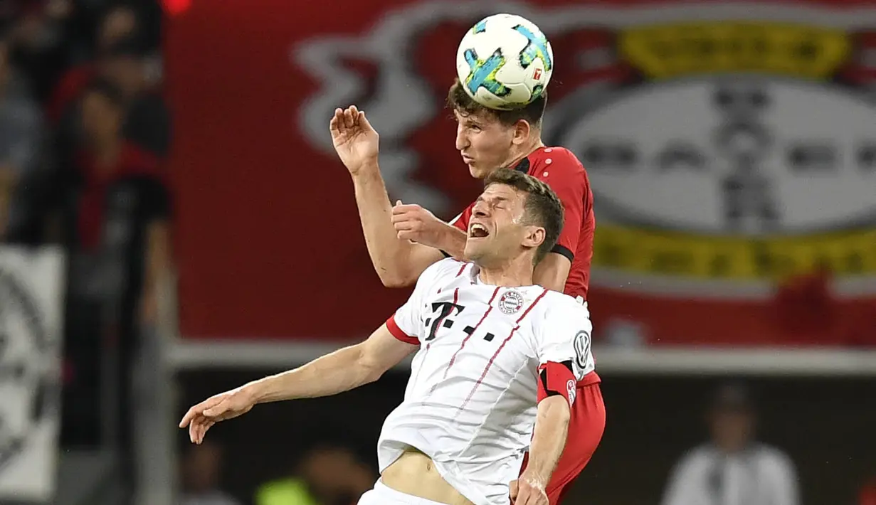 Penyerang Bayern Munchen, Thomas Mueller, duel udara dengan bek Bayer Leverkusen, Panagiotis Retsos, pada laga DFB Pokal di Stadion BayArena, Selasa (17/4/2018). Bayern Munchen menang 6-2 atas Bayer Leverkusen. (AP/Martin Meissner)