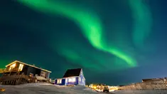 Aurora Borealis menerangi langit malam di atas rumah-rumah penduduk di Nuuk, Greenland, pada 23 Januari 2026. Cahaya hijau bersinar menghiasi langit kota Nuuk, Greenland, pada Jumat 23 Januari 2026 waktu setempat. (Jonathan NACKSTRAND/AFP)