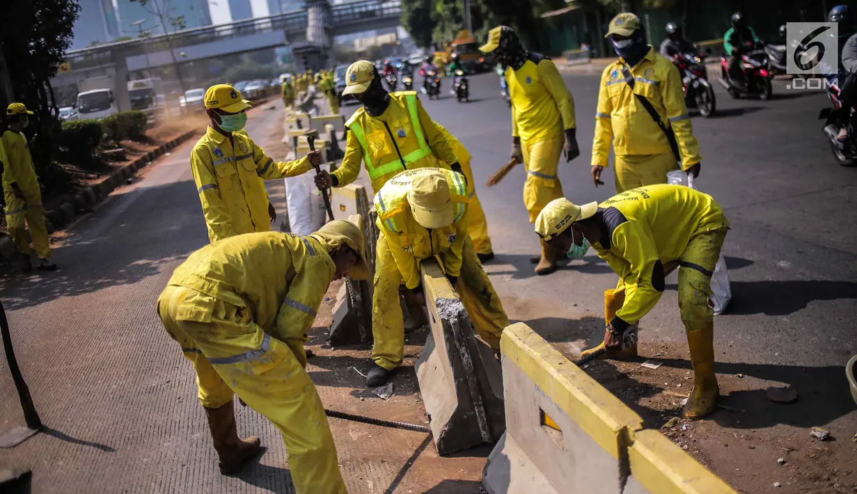 Petugas Dinas Bina Marga DKI Jakarta memperbaiki separator busway di kawasan Jalan Gatot Subroto, Jakarta, Selasa (1/10/2019). Separator busway dirusak massa saat terjadi bentrok antara polisi dengan demonstran di kawasan tersebut. (Liputan6.com/Faizal Fanani)