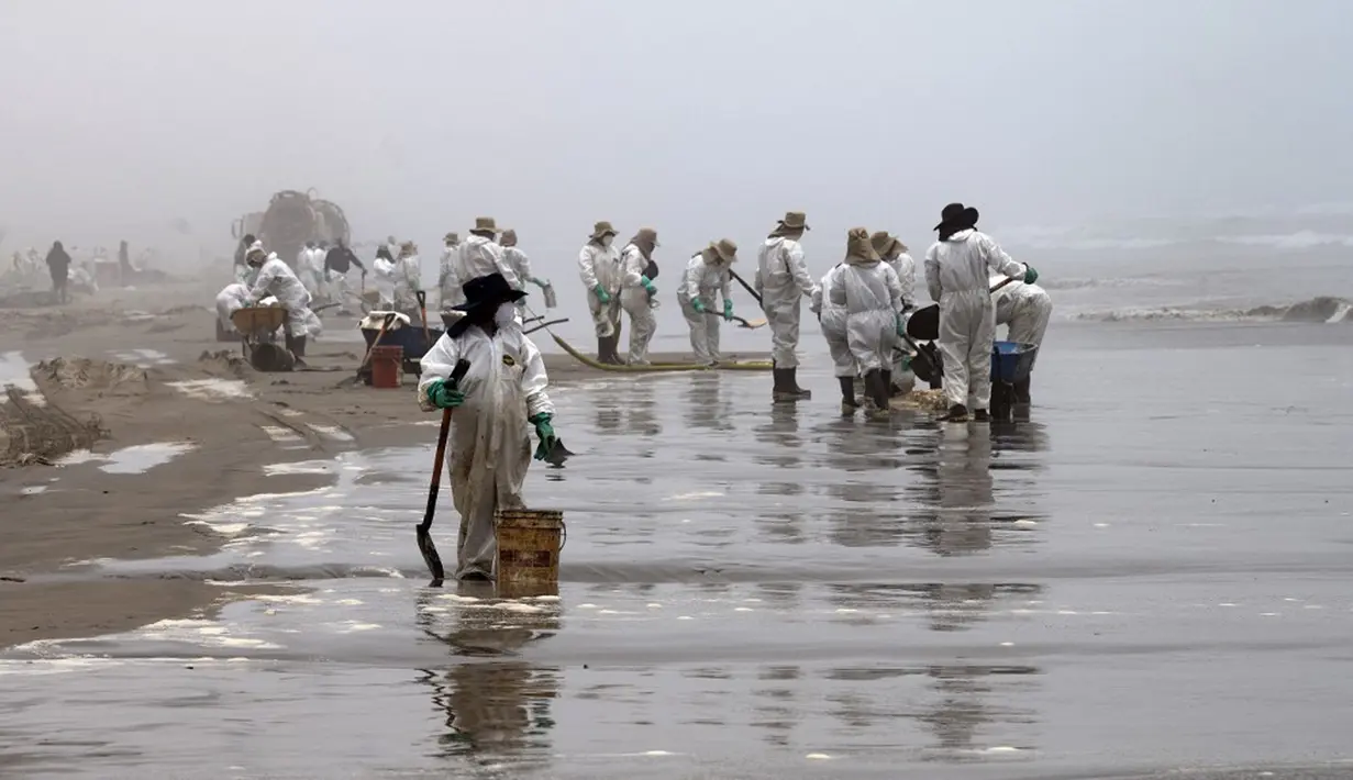 Petugas kebersihan bekerja untuk mengeluarkan minyak dari Pantai Cavero di Callao, Peru, 26 Januari 2022. Pembersihan Pantai Cavero dari tumpahan minyak kapal tanker Mare Doricum yang dihantam gelombang akibat letusan gunung berapi Tonga masih terus dilakukan. (Cris BOURONCLE/AFP)