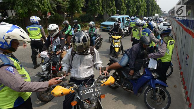 Polisi lalu lintas melakukan tilang terhadap pengendara motor saat razia Operasi Patuh Jaya 2019 di kawasan Kebon Nanas, Jakarta, Kamis (29/8/2019). Operasi ini diharapkan dapat meningkatkan kepatuhan dan ketertiban dalam berlalu lintas serta mengurangi angka kecelakaan. (merdeka.com/Imam Buhori)