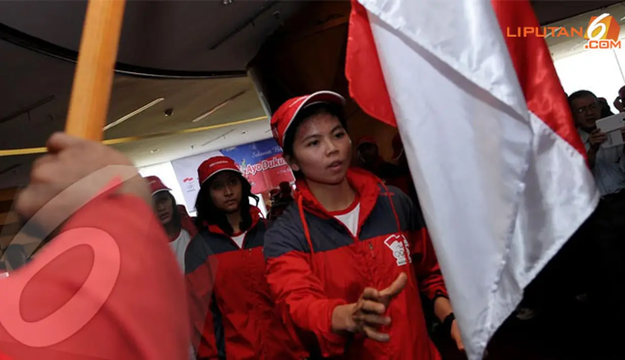 Pebulutangkis Greysia Polii bersiap mencium Sang Merah Putih saat upacara pengukuhan dan pelepasan atlit Sea Games 2013 Myanmar di Jakarta pada 2 Desember 2013 (Liputan6.com/Helmi Fithriansyah)