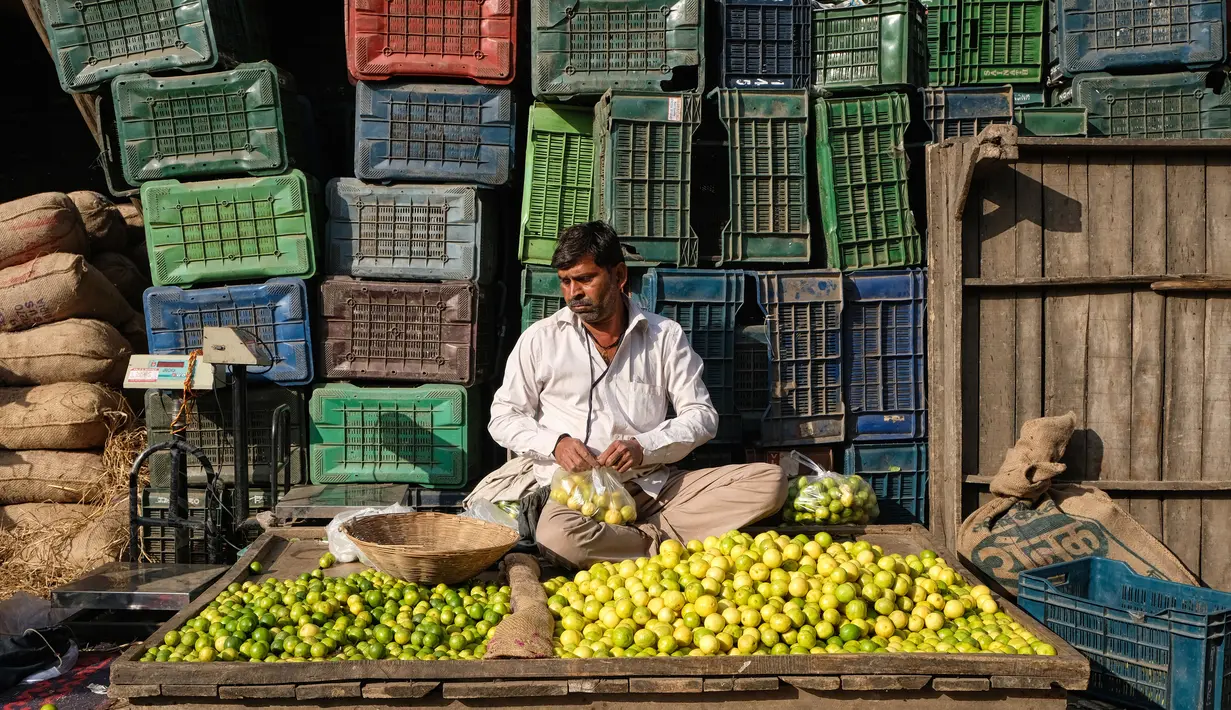 Seorang pegadang memasukan lemon kedalam plastik saat dia menunggu pelanggan di pasar grosir buah dan sayuran di New Delhi, India (27/3). Dari pasar tradisional hingga mal megah modern, Delhi memiliki segalanya untuk ditawarkan kepada pelanggan. (AFP Photo/Noemi Cassanelli)