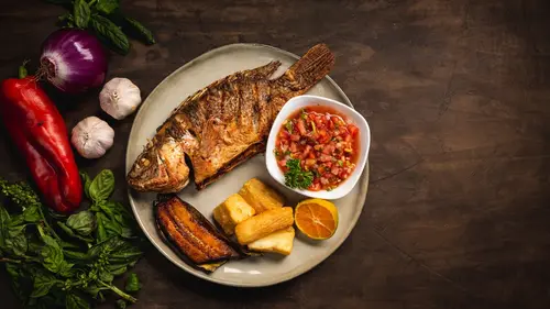 Ikan nila goreng berwarna keemasan disajikan dengan sambal dan lalapan