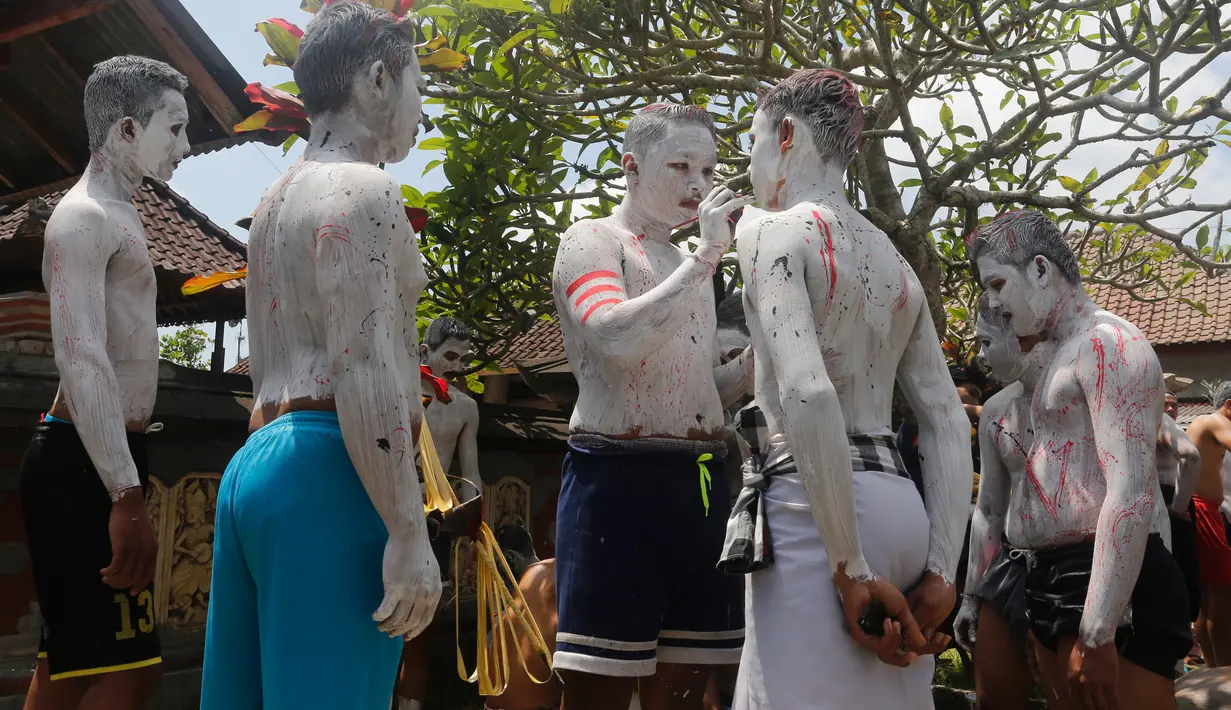 Para pemuda melukis diri mereka untuk persiapan ritual Hindu yang disebut "Grebeg" di Desa Tegallalang, Bali, Rabu (30/1). Tradisi ritual berkeliling kampung dengan riasan tubuh warna-warni itu dipercaya sebagai penangkal Roh jahat. (AP/Firdia Lisnawati)