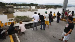 Beberapa warga berkerumun di tepi jembatan yang terputus akibat serangan topan Rammasun, di Batangas, Manila, (17/7/2014). (REUTERS/Erik De Castro)