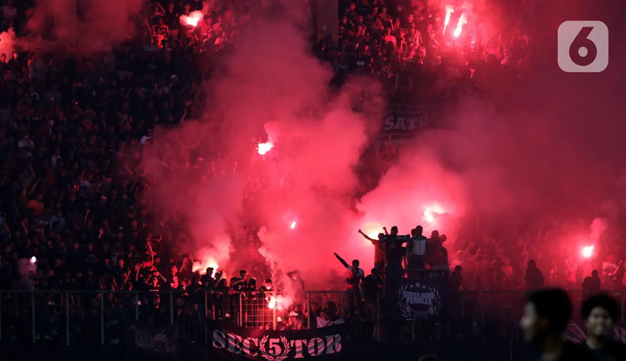 Suporter menyalakan flare saat menyaksikan laga Persija melawan Sabah FC pada laga uji coba internasional di Stadion Patriot Candrabhaga, Kota Bekasi, Minggu (5/6/2022). Pertandingan sepakbola kembali bisa disaksikan secara langsung setelah pemerintah melonggarkan aturan pemakaian masker di luar ruangan. (Liputan6.com/Helmi Fithriansyah)