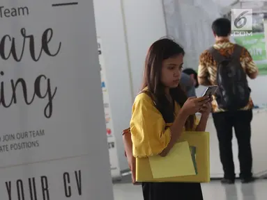 Pencari kerja melihat-lihat ponsel saat gelaran Job For Career Festival 2019 di area Stadion GBK, Jakarta, Selasa (5/3). Berdasarkan data BPS per Agustus 2018 sebanyak tujuh juta orang Indonesia menganggur. (Liputan6.com/Helmi Fithriansyah)