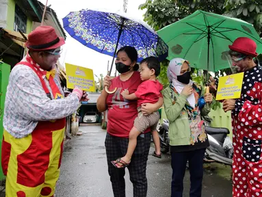 Dua badut menjemput dan mengantar warga untuk mengikuti vaksinasi COVID-19 di Pinang, Tangerang, Banten, Selasa (14/9/2021). Aksi yang dilakukan Taman Baca Badut Syariah itu dilakukan untuk mengajak warga mengikuti vaksinasi COVID-19 guna meningkatkan herd imunity. (Liputan6.com/Angga Yuniar)
