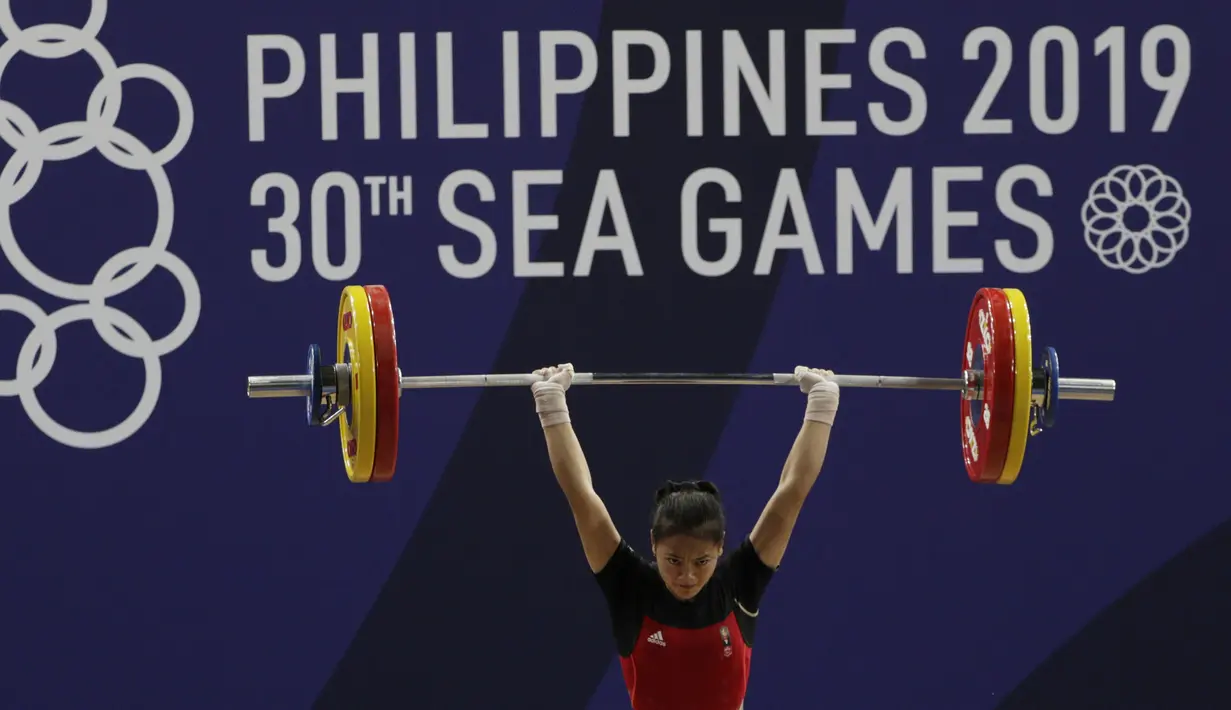 Lifter Aisyah Windy melakukan angkatan saat SEA Games 2019 cabang angkat besi nomor 49 kg di Stadion Rizal Memorial, Manila, Minggu (1/12). Dirinya meraih emas dengan total angkatan 104 kg. (Bola.com/M Iqbal Ichsan)