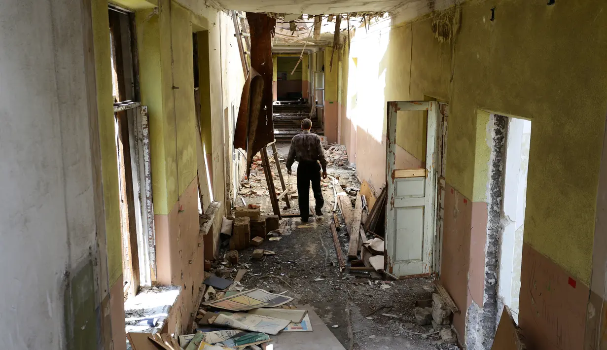 Seorang pria berjalan di dalam Sekolah Nomor 2 yang hancur terkena hantaman misil di kota Krasnogorivka yang terletak langsung di garis depan wilayah timur Ukraina, 21 Mei 2018. Tiga dari lima sekolah di kota tersebut sudah ditutup. (Aleksey FILIPPOV/AFP)