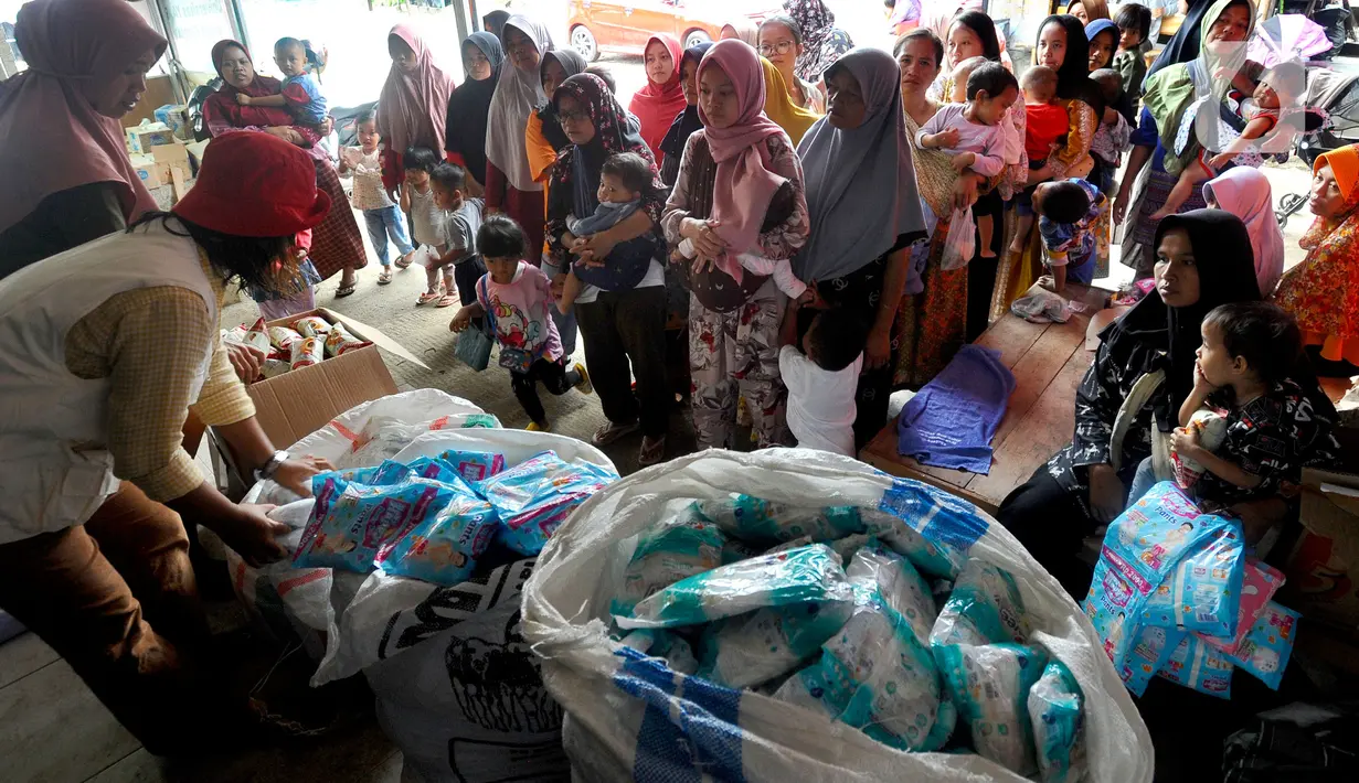 Warga antre mendapatkan pampers dan biskuit bagi anak-anak di Posko pengungsian Mangunkerta, Cianjur, Jumat (23/12/2022). Lebih dari sebulan sejak musibah gempa bumi 5,2 SR sejumlah warga masih tinggal di pengungsian dengan bantuan kebutuhan hidup dari para donatur. (merdeka.com/Arie Basuki)