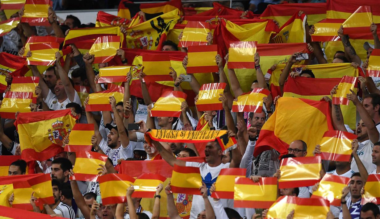 Suporter Real Madrid membentangkan bendera Spanyol saat pertandingan melawan Espanyol di Santiago Bernabeu, Spanyol (1/10). Warga Catalonia mengikuti referendum Minggu (1/10) untuk memutuskan memerdekakan diri atau tidak. (AFP Photo/Gabriel Bouys)