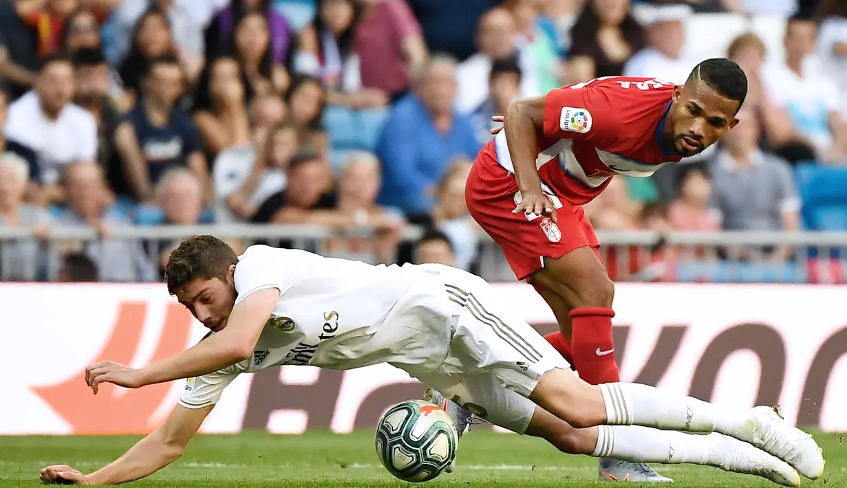 Gelandang Real Madrid, Federico Valverde, dijatuhkan gelandang Granada, Yangel Herrera, pada laga La Liga Spanyol di Stadion Santiago Bernabeu, Madrid, Sabtu (5/10). Madrid menang 4-2 atas Granada. (AFP/Pierre-Philippe Marcou)