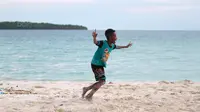 Seorang bocah melakukan selebrasi usai mencetak gol saat bermain bola dekat pantai di Desa Matwaer, Kei Kecil, Maluku (25/12/2017). Bermain bola di pasir menjadi daya tarik tersendiri bagi anak-anak dan pemuda desa. (Bola.com/Nick Hanoatubun)