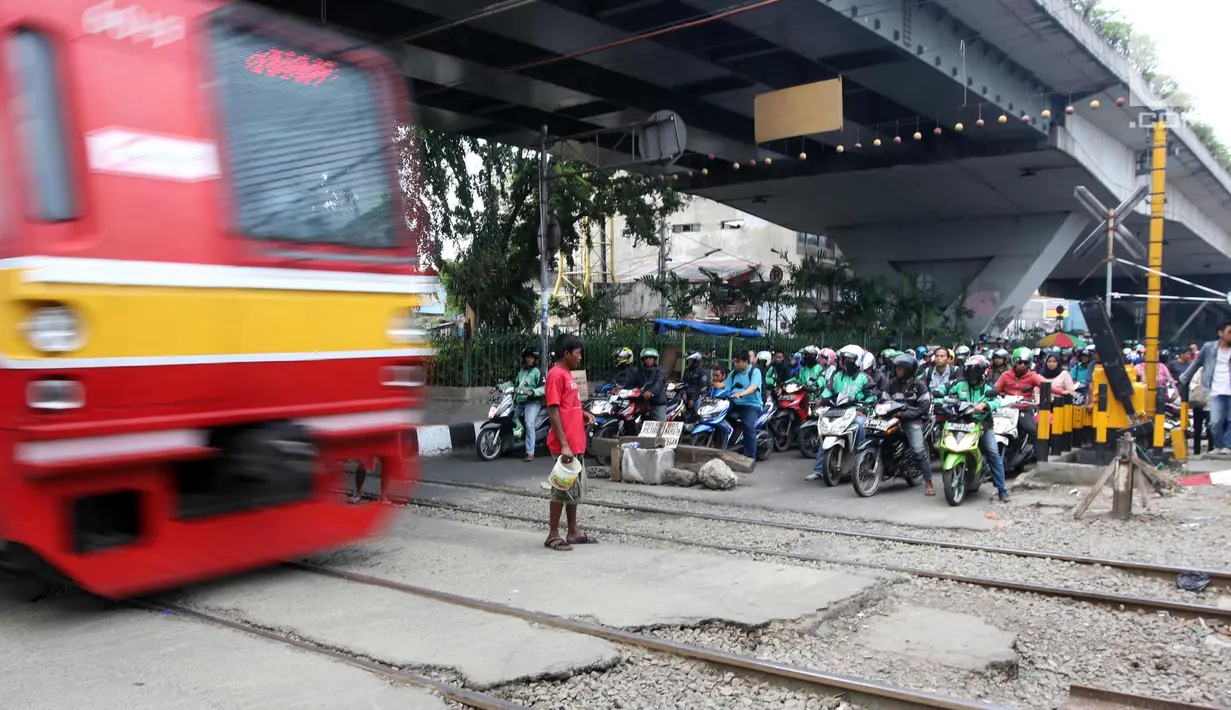Sejumlah pengendara motor menunggu kereta melintas di perlintasan kereta api di kawasan Roxy, Jakarta, Rabu (21/3). Pembukaan celah untuk akses sepeda motor di pintu perlintasan kereta api tersebut sangat membahayakan. (Liputan6.com/Arya Manggala)