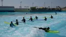 Peselancar mendapat instruksi di kolam ombak Wave Park di Siheung, Korea Selatan, 18 Oktober 2020. Korea Selatan memiliki kolam ombak terbesar di dunia dengan teknologi Wavegarden Cove yang memiliki beberapa modul produksi gelombang dan menjadi kolam gelombang dengan jumlah terbesar. (Ed JONES/AFP)