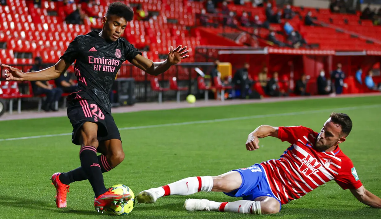 Pemain Real Madrid Vinicius Junior (kiri) memperebutkan bola dengan pemain Granada Quini pada pertandingan La Liga di Stadion Los Carmenes, Granada, Spanyol, Kamis (13/5/2021). Real Madrid menang telak 4-1 atas Granada. (AP Photo/Fermin Rodriguez)