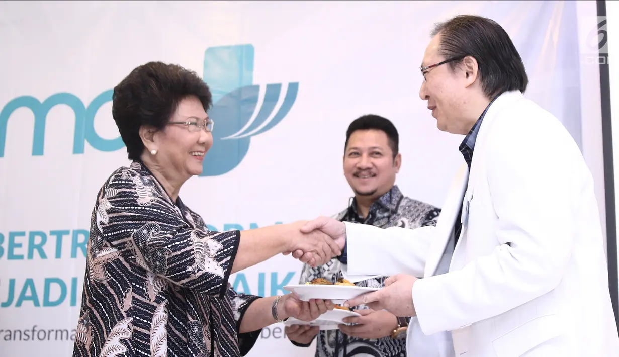 Ketua Yayasan Karya Alpha Omega Non Rawung memberi potongan tumpeng ke Ketua Komite Medik RS EMC Sentul dr Sendjaja Muljadi  saat soft launching RS EMC di Sentul, Bogor, Jawa Barat, Sabtu (21/4). (Liputan6.com/Herman Zakharia)