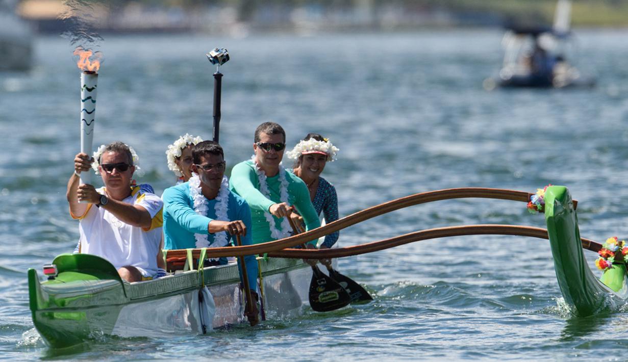 Mantan atlet kano, Rubens Pompeu, membawa obor Olimpiade Rio dengan menaiki perahu di Danau Paranoa, Brasilia, Brasil, (3/5/2016). (AFP/Yasuyoshi Chiba)