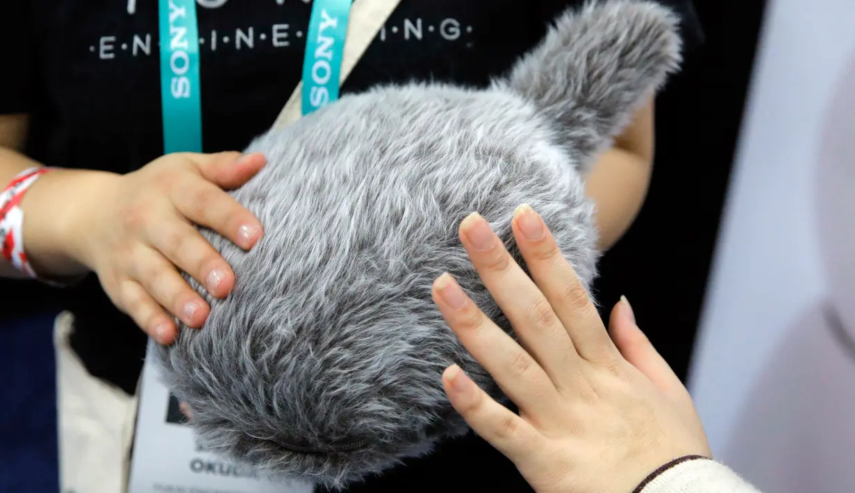 Pengunjung memegang robot Qoobo saat pameran teknologi CES 2020 di Las Vegas, Amerika Serikat, Minggu (5/1/2020). Qoobo dapat mengibaskan ekornya saat dibelai. (AP Photo/John Locher)