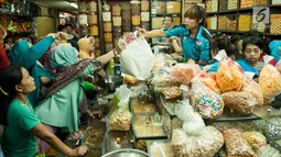Pembeli melakukan transaksi dengan penjual kue kering di toko kue Pasar Jatinegara, Jakarta, Selasa (14/6). Pasar ini merupakan salah satu pasar kue kering yang selalu ramai diserbu para pelanggan. (Liputan6.com/Gempur M Surya)