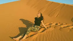 Wanita kelahiran tahun 2004 ini tampak menikmati liburannya di Gurun Sahara. Duduk di gurun yang begitu bersih, Aurora tampil santai dengan baju hitam dan celana panjang army. (Liputan6.com/IG/@auroraribero)