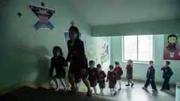 Anak-anak sekolah dasar dengan memakai masker tiba untuk mengikuti kelas di Sekolah Dasar Hasin di Distrik Sosong di Pyongyang, Rabu (3/6/2020). Korea Utara membuka kembali sekolah - sekolah di bulan ini setelah sebelumnya meliburkan karena kekhawatiran penyebaran virus corona. (KIM Won Jin / AFP)