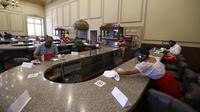 Pelayan mengenakan masker dan pelindung wajah untuk mencegah penyebaran virus corona COVID-19 saat membersihkan meja di Restoran Sanborns of the Azulejos, Mexico City, Meksiko, Rabu (1/7/2020). (AP Photo/Eduardo Verdugo)