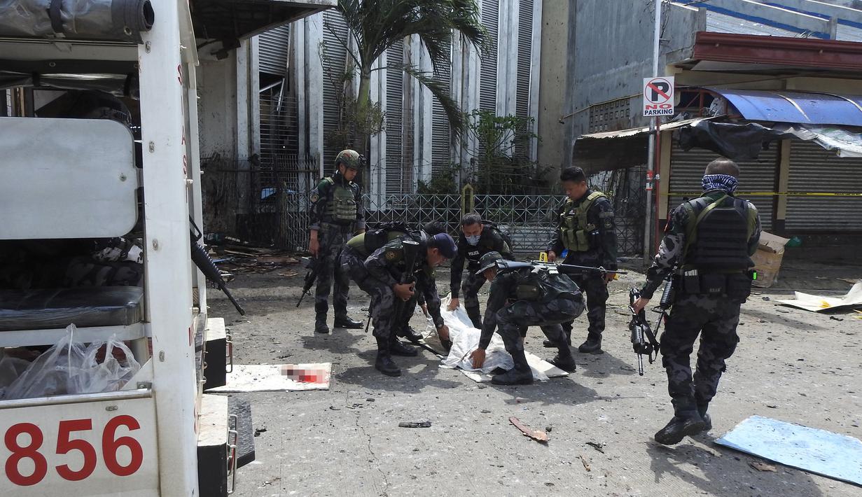 Polisi mengevakuasi kantong jenazah pasca ledakan bom di Gereja Katolik Jolo, Filipina Selatan, Minggu (27/1). Dua bom meledak, Sedikitnya 27 orang tewas dan 57 orang lainnya mengalami luka. (Nickee Butlangan/AFP)
