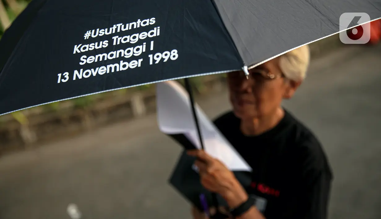Anggota Jaringan Solidaritas Korban untuk Keadilan (JSKK) menggunakan payung hitam bertuliskan #UsutTuntas "Kasus Tragedi Semanggi I 13 November 1998 saat melakukan Aksi Kamisan ke-795 di seberang Istana Merdeka, Jakarta, Kamis (16/11/2023). (Liputan6.com/Faizal Fanani)