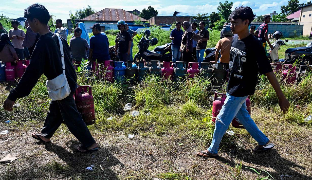 Warga membawa tabung gas di sebuah stasiun pengisian dan pembelian LPG setelah banjir bandang di Banda Aceh pada Rabu 17 Desember 2025. Kelangkaan gas masih terjadi di Kota Banda Aceh. (CHAIDEER MAHYUDDIN/AFP)
