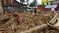 Orang-orang berjalan di atas puing-puing di daerah yang terkena banjir bandang di Masamba, Sulawesi Selatan, Rabu (15/7/2020). Banjir bandang akibat tingginya curah hujan tersebut mengakibatkan 16 orang meninggal dunia dan puluhan warga dilaporkan masih dalam pencarian. (AP/Khaizuran Muchtamir)