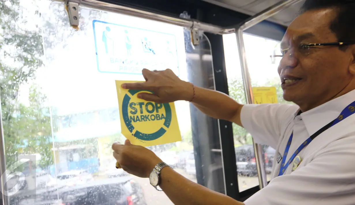 Direktur Utama Perum PPD, Pande Putu Yasa menempel stiker sosialisasi di bus transjakarta saat dilangsungkan tes urine di Pool Bus Perum PPD di Tangerang Selatan, Senin (20/3). (Liputan6.com/Helmi Afandi)