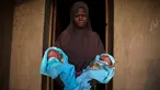 Seorang wanita muslim menggendong saudara laki-laki kembarnya yang berumur 4 hari di depan pintu rumahnya di Igbo Ora, Negara Bagian Oyo, Nigeria pada 3 April 2019.  Igbo Ora, sebuah wilayah di bagian barat daya Nigeria ini terkenal dengan anak-anaknya yang terlahir kembar. (REUTERS/Afolabi Sotunde)