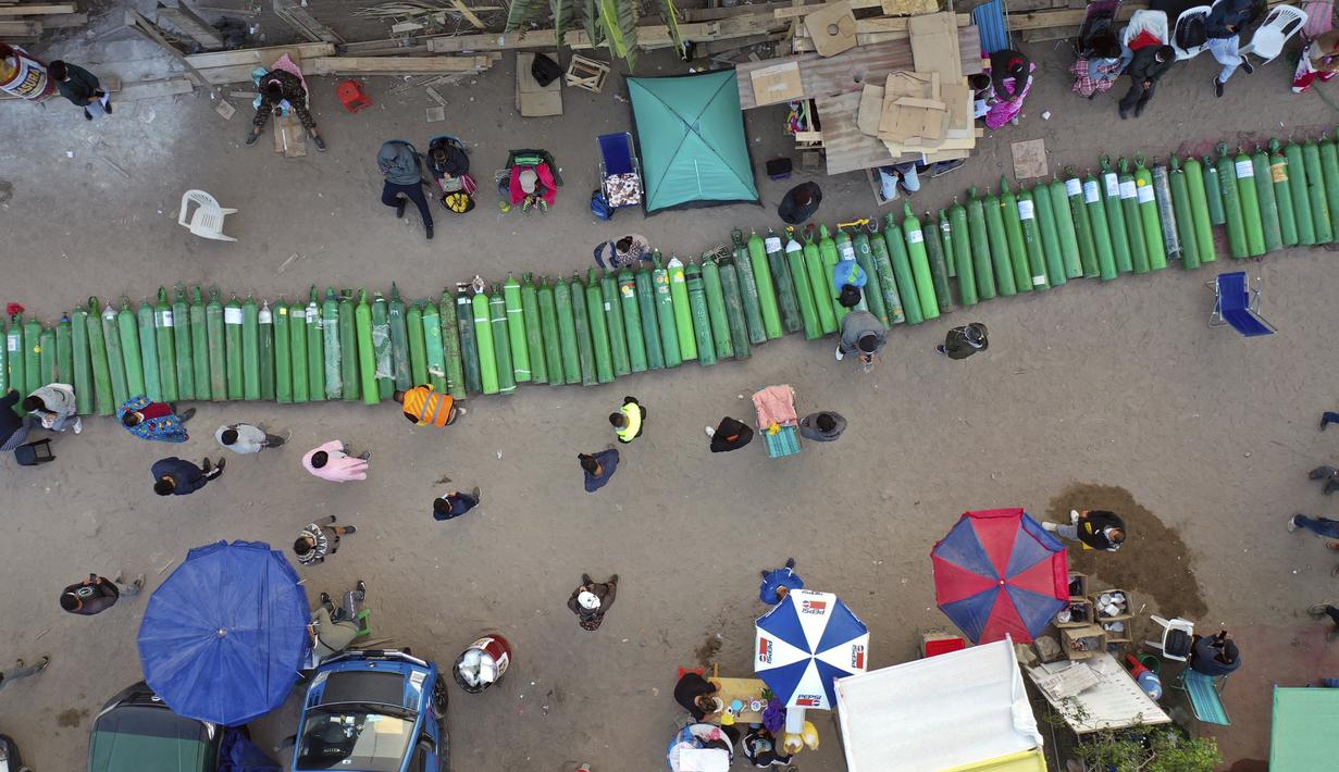 Lusinan tabung oksigen kosong tergeletak di jalan ketika orang-orang menunggu toko buka untuk mengisi tabung mereka di Villa El Salvador, Lima, Peru, Selasa (6/4/2021). Warga Peru terus berjuang mendapatkan oksigen medis untuk merawat pasien COVID-19. (AP Photo/Rodrigo Abd)